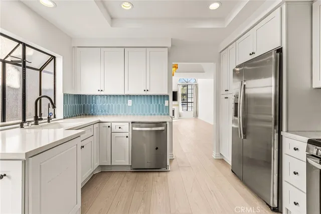 a kitchen with a sink cabinets stainless steel appliances and a window