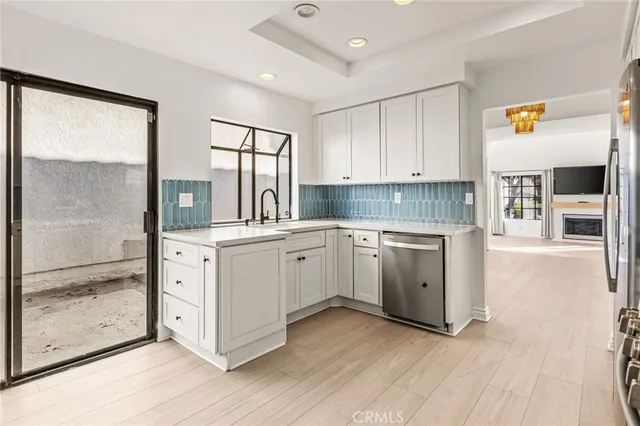 a kitchen with white cabinets and wooden floor