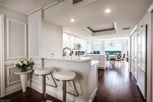 a kitchen with a table chairs stove and white cabinets with wooden floor