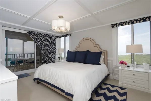 a bedroom with a bed a chandelier and dresser