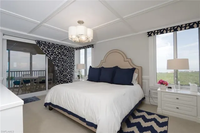 a bedroom with a bed a chandelier and dresser