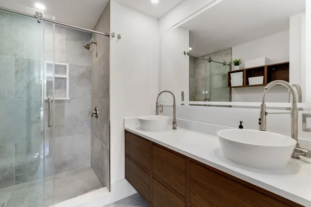 a bathroom with a double vanity sink mirror and shower