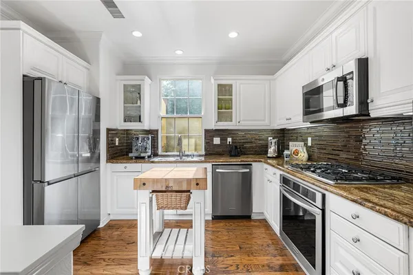 a kitchen with stainless steel appliances granite countertop a refrigerator a stove and a sink