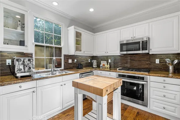a kitchen with granite countertop white cabinets and white stainless steel appliances