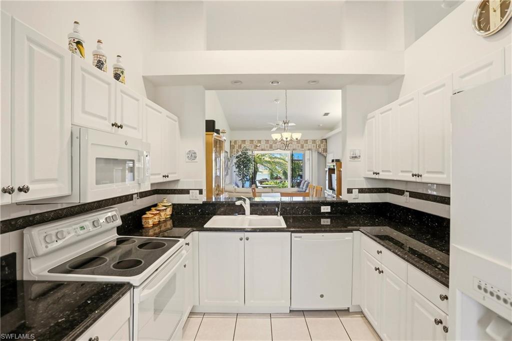 511 Joseph Court, Unit 2 Naples, FL 34104 - Photo 12 of 50 a kitchen with a sink dishwasher a stove and white cabinets next to a window