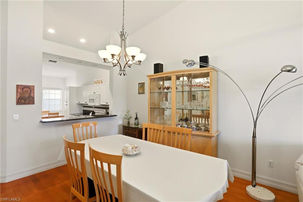 511 Joseph Court, Unit 2 Naples, FL 34104 - Photo 22 of 50 a view of a dining room with furniture a chandelier and wooden floor