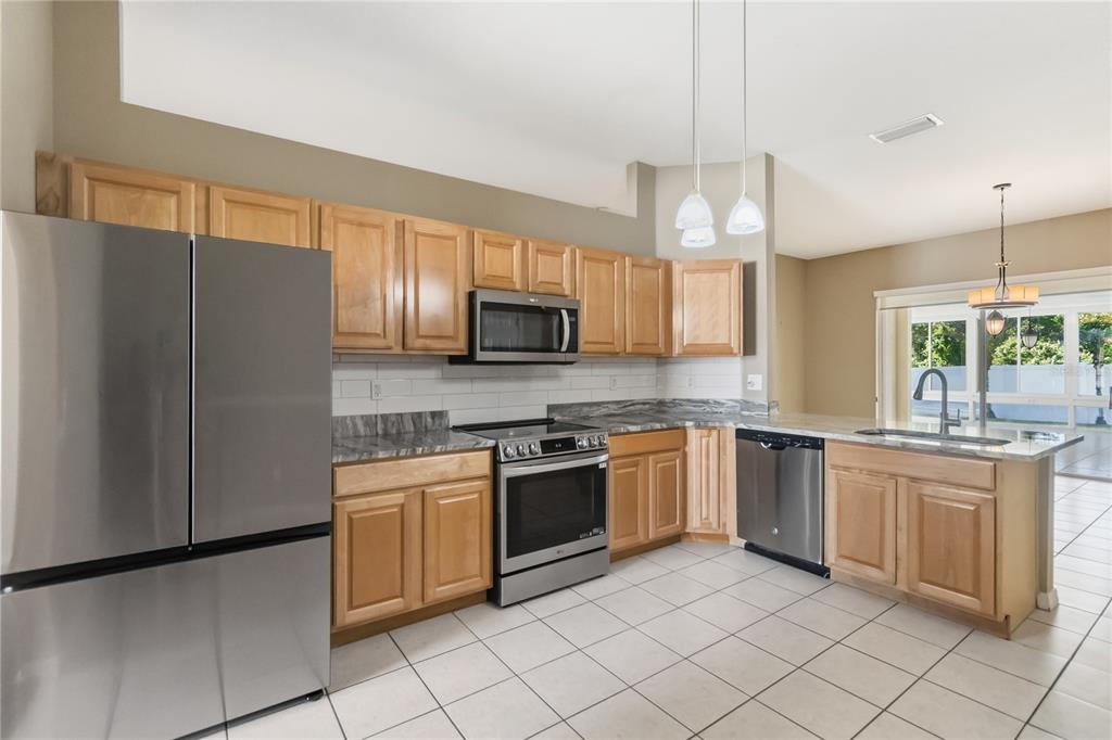 677 Buckhaven Loop Ocoee, FL 34761 - Photo 8 of 41 a kitchen with stainless steel appliances granite countertop a stove a sink and a refrigerator