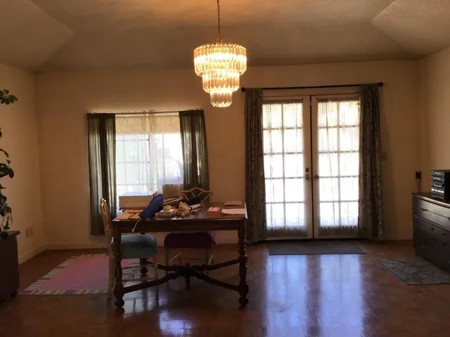 a dining room with chandelier and wooden floor