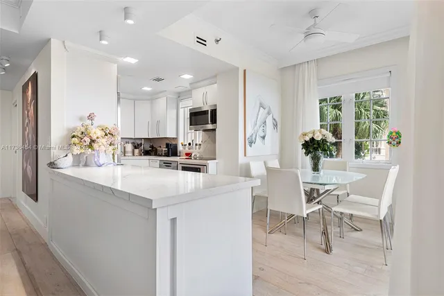 a kitchen with stainless steel appliances kitchen island granite countertop a table chairs and a refrigerator