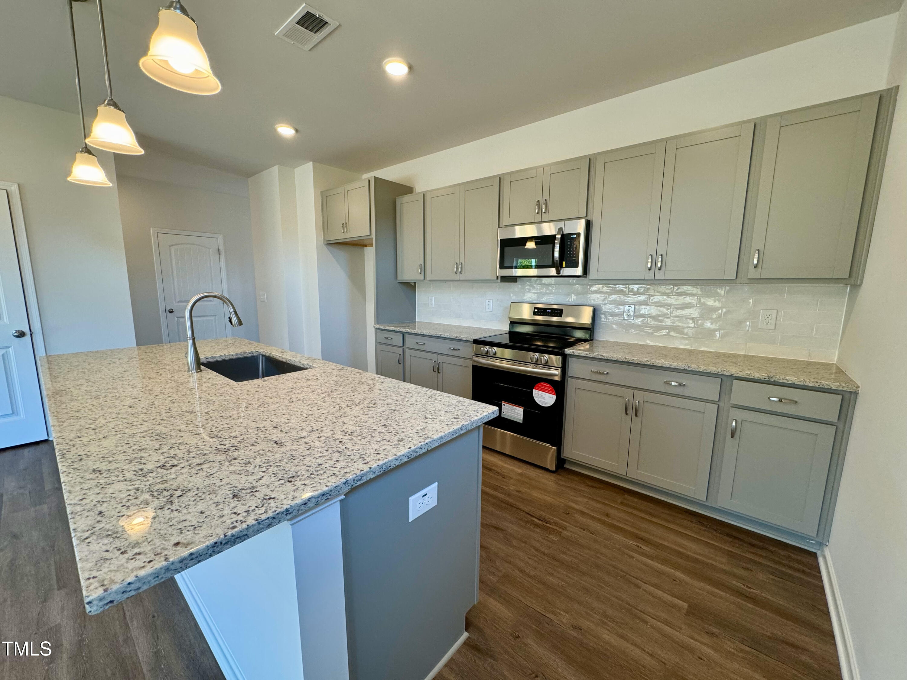 134 Commons Circle, Unit 232 Clayton, NC 27520 - Photo 5 of 37 a kitchen with stainless steel appliances granite countertop a sink stove refrigerator and cabinets