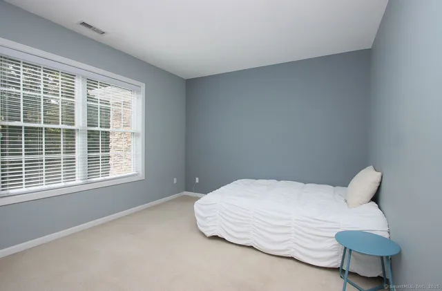a bedroom with a bed and next to a window