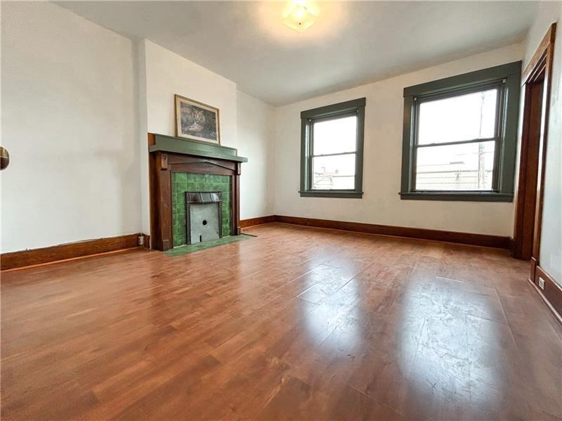 219 Brownsville Road Pittsburgh, PA 15210 - Photo 7 of 30 an empty room with wooden floor fireplace and windows