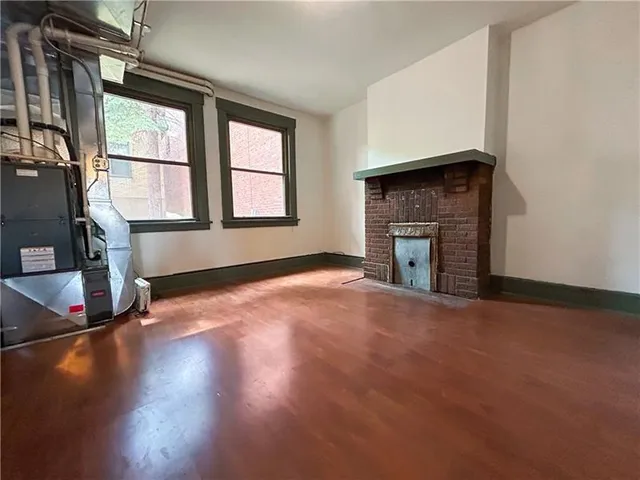 an empty room with wooden floor fireplace and windows