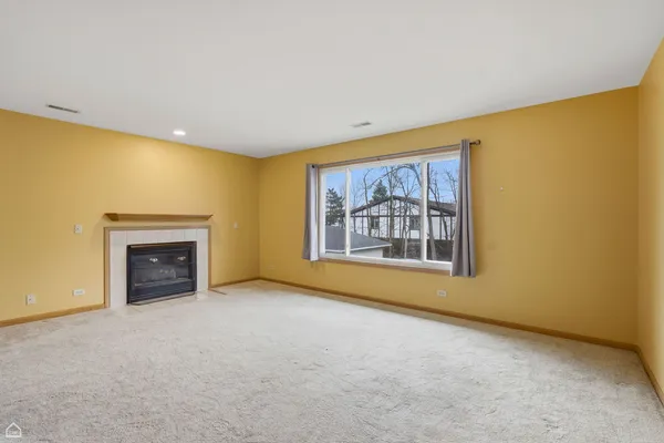 a view of an empty room with a fireplace and a window
