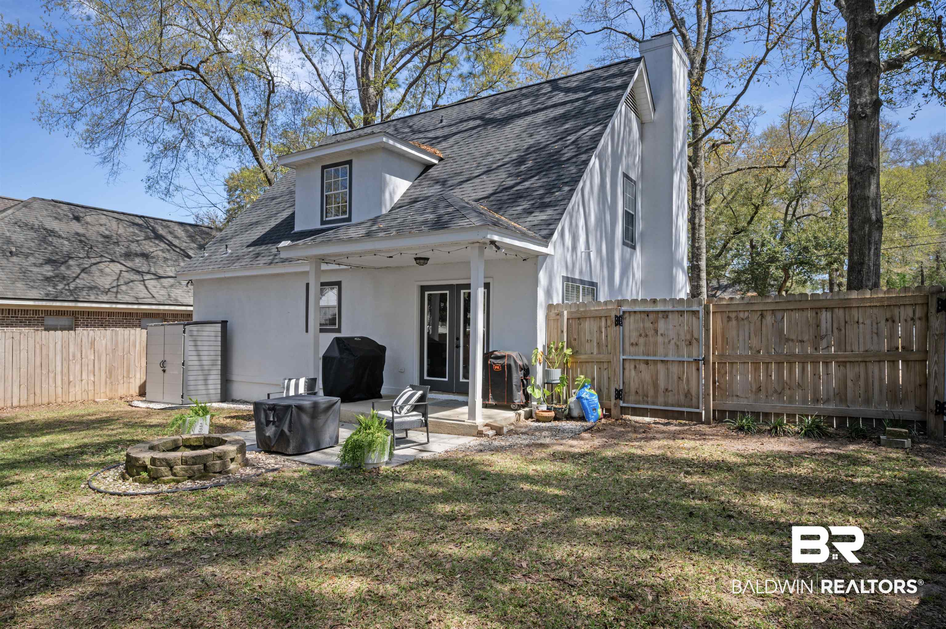 1066 Linlen Avenue Mobile, AL 36609 - Photo 21 of 22 Back of house featuring stucco siding, a fenced backyard, a fire pit, a shingled roof, and a lawn