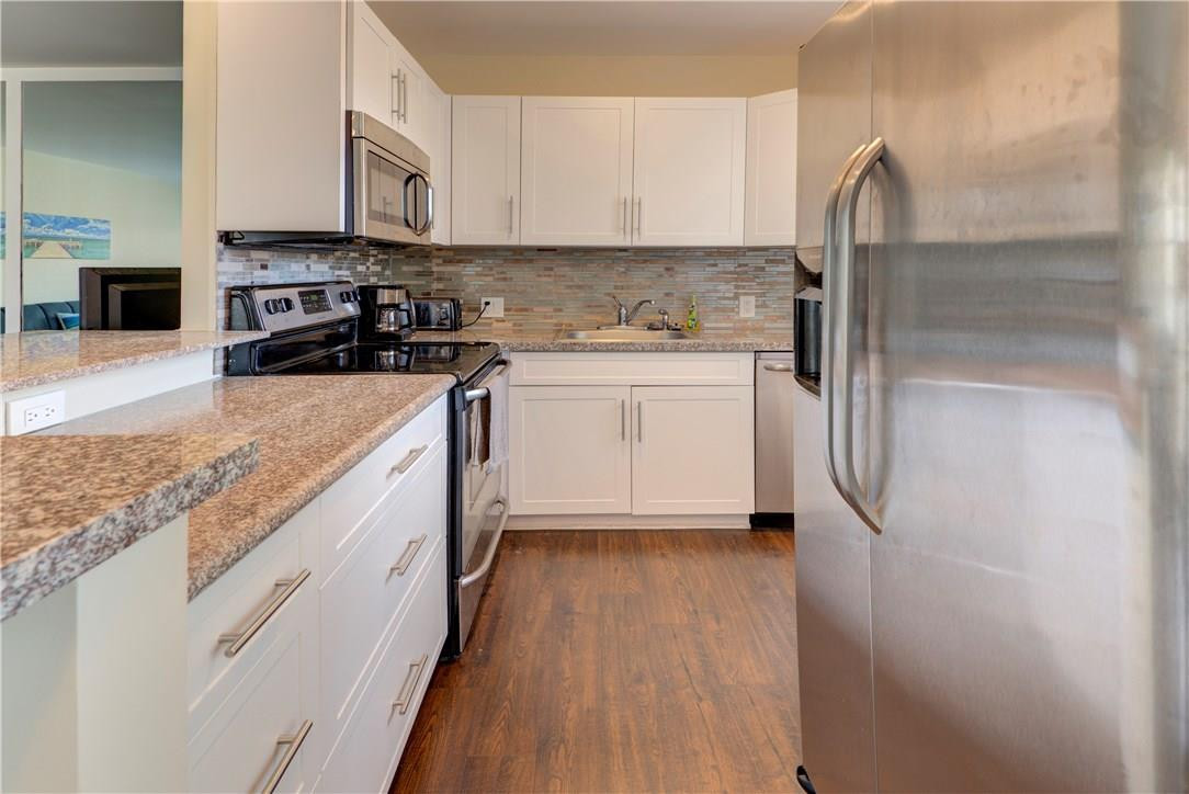 144 Dorset D, Unit 144 Boca Raton, FL 33434 - Photo 4 of 20 a kitchen with stainless steel appliances granite countertop a refrigerator a stove and a sink with wooden floor