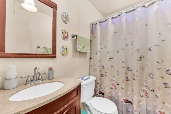a bathroom with a granite countertop sink mirror vanity and toilet
