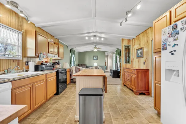 a large white kitchen with stainless steel appliances kitchen island granite countertop a lot of counter space and a window
