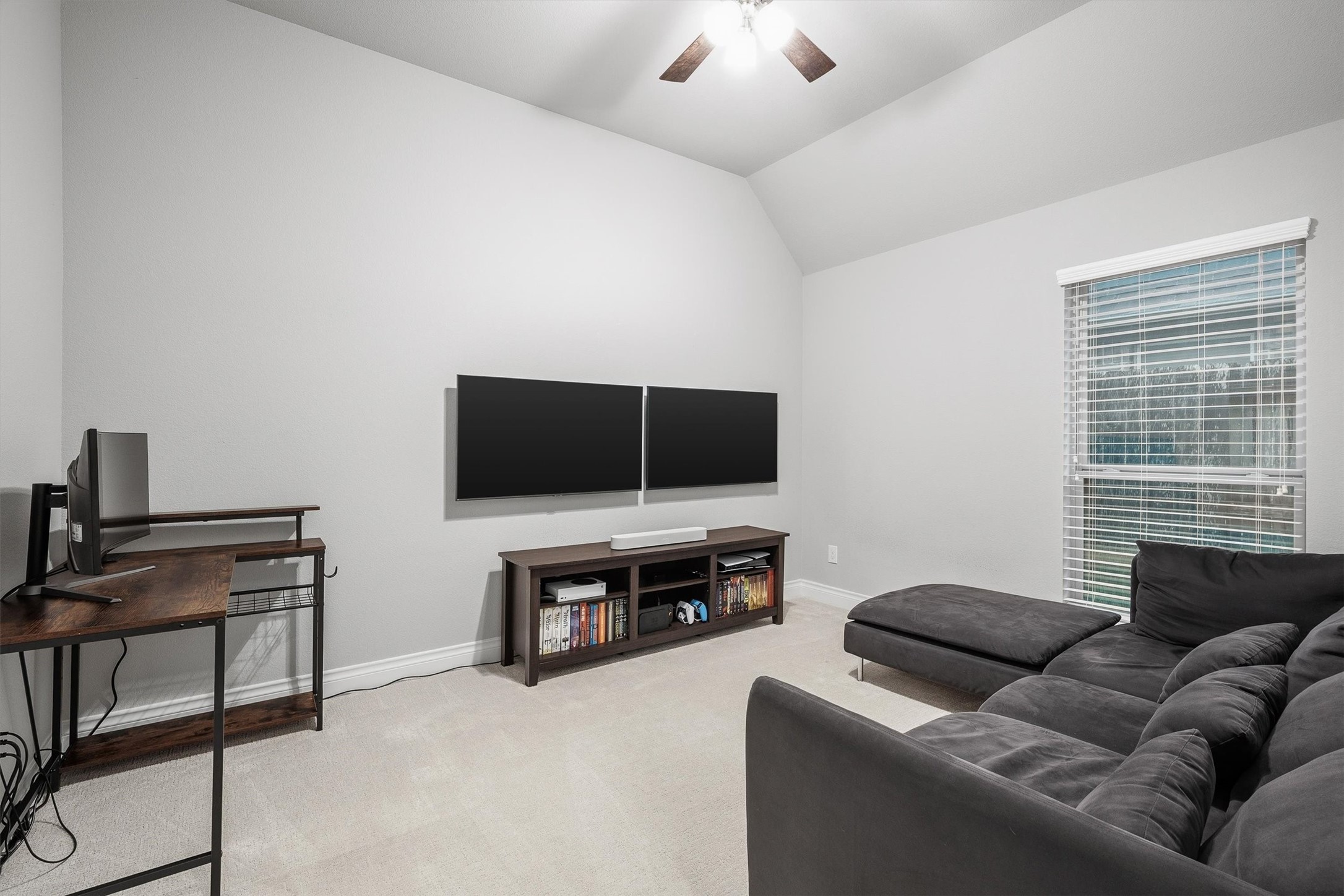 29118 Lantana Ridge Court Fulshear, TX 77441 - Photo 11 of 29 This bedroom offers soft carpeted floors, a window for natural light, a vaulted ceiling, and a modern ceiling fan, providing a comfortable and airy space.
