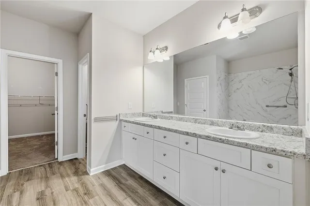 a bathroom with a granite countertop double vanity sink and mirror