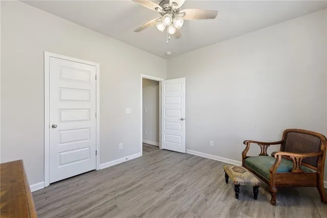 an empty room with wooden floor a ceiling fan and windows