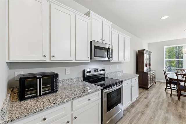 a kitchen with granite countertop white cabinets and stainless steel appliances