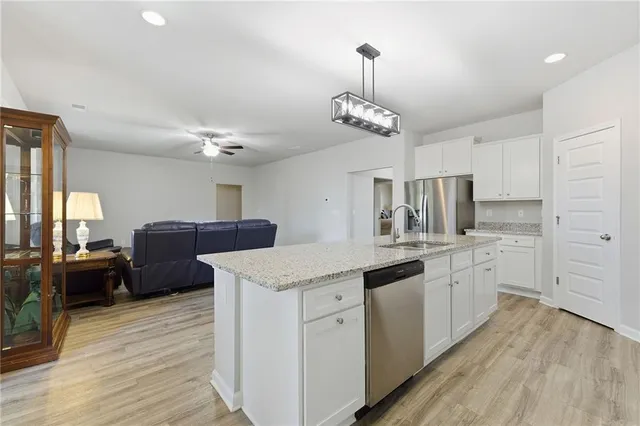 a open kitchen with stainless steel appliances granite countertop a sink dishwasher a stove a dining table and chairs with wooden floor