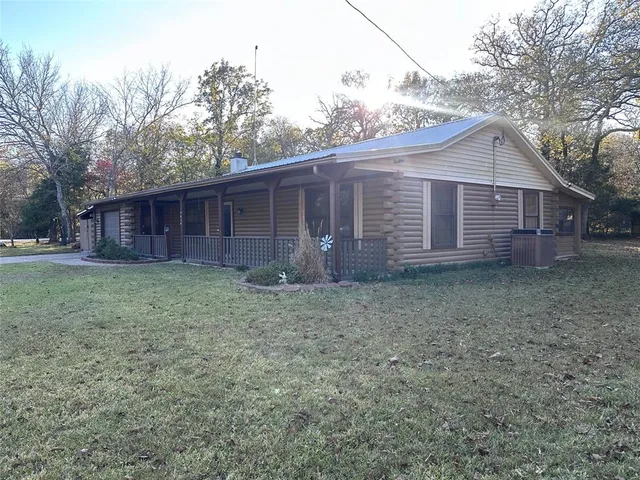 a view of a house with a yard and large trees
