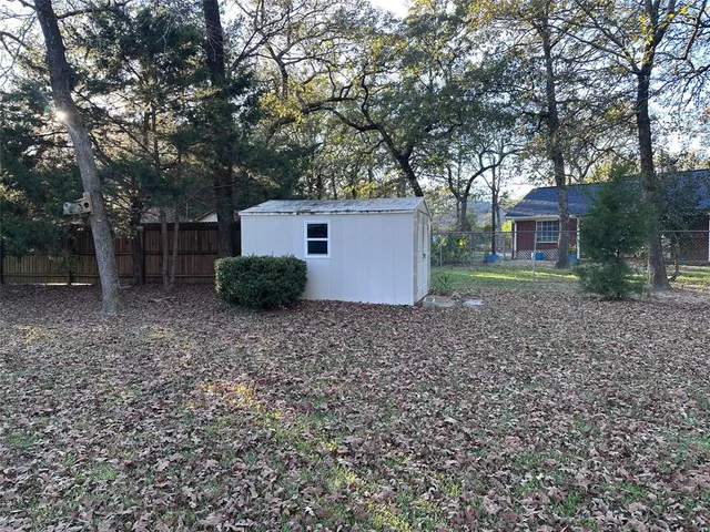 a backyard of a house with plants and large tree