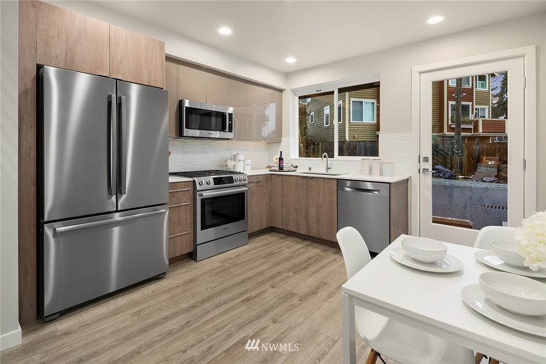 10158 Holman Road Northwest Seattle, WA 98133 - Photo 8 of 21 a kitchen with stainless steel appliances granite countertop a refrigerator a stove a sink dishwasher a dining table and chairs with wooden floor