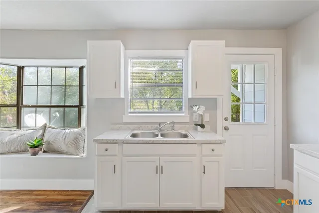 a bathroom with a granite countertop sink and a window