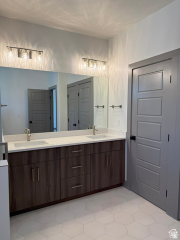 8087 South 615 East, Unit 3 Sandy, UT 84070 - Photo 14 of 23 Dual vanity featuring a white countertop with integrated sinks, brushed nickel faucets, and wood-finish cabinetry