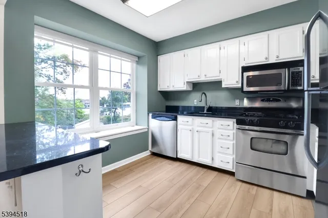 a kitchen with granite countertop a stove a sink and dishwasher wooden cabinets with wooden floor