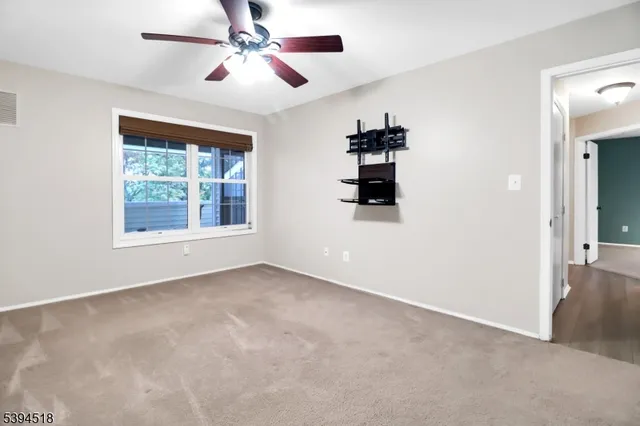an empty room with windows and fan