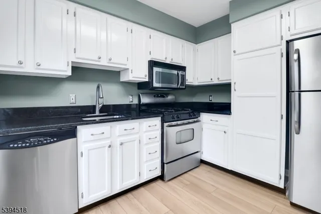 a kitchen with white cabinets white stainless steel appliances and sink