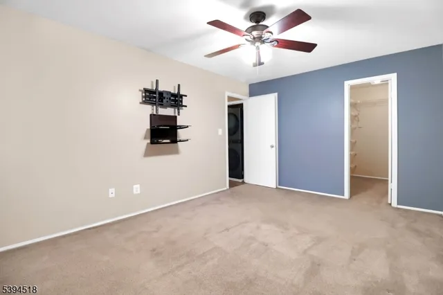 an empty room with closet and a chandelier fan