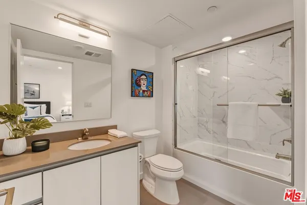 a bathroom with a shower sink vanity mirror and toilet