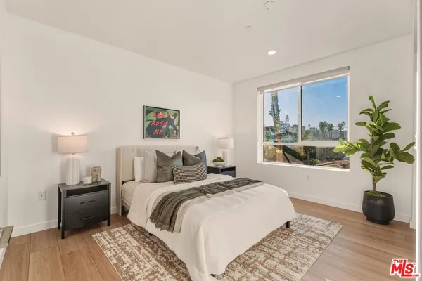 a bedroom with a bed a couch and a potted plant