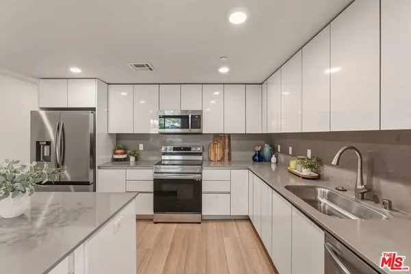 a kitchen with stainless steel appliances granite countertop a sink stove and refrigerator