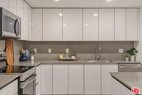 a kitchen with cabinets stainless steel appliances and sink