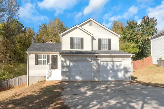 a view of a white house with a large space and large trees