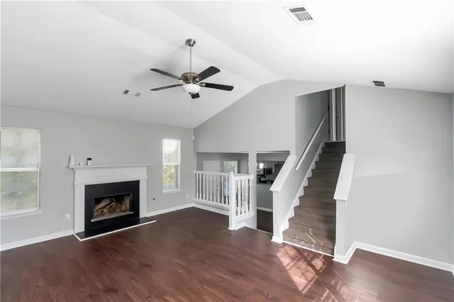 a view of an empty room with wooden floor fireplace and a window