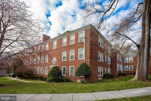 a front view of a building with garden and trees