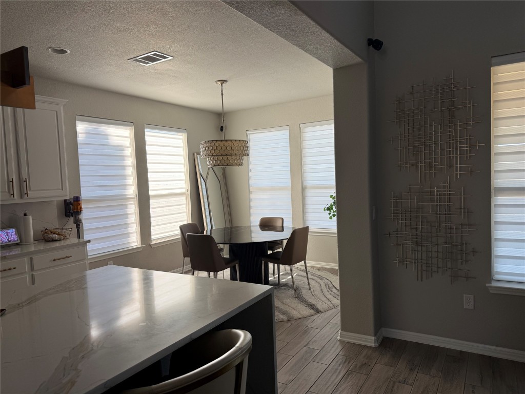 Undisclosed Address Leander, TX 78641 - Photo 7 of 8 Kitchen with white cabinets, plenty of natural light, pendant lighting, wood tiled floors, and a textured ceiling