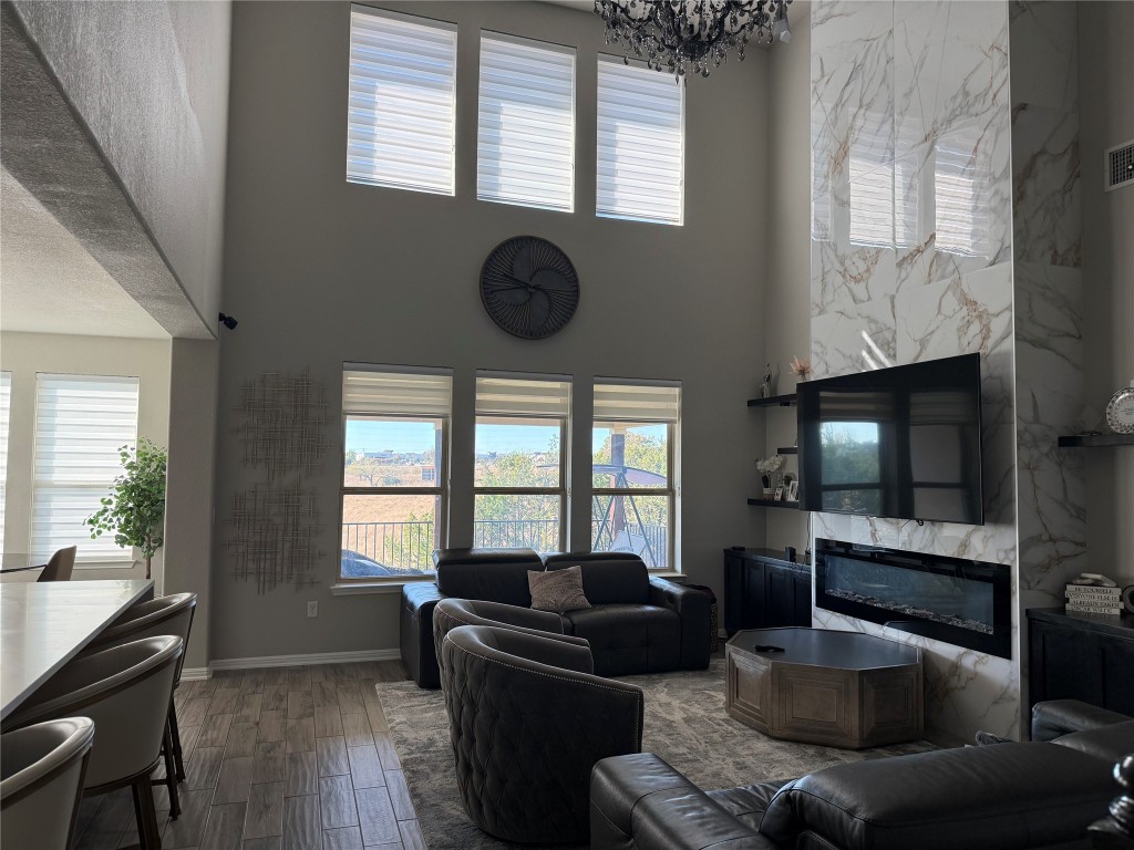 Undisclosed Address Leander, TX 78641 - Photo 8 of 8 Living room with wood finished floors, a premium fireplace, a high ceiling, and a chandelier