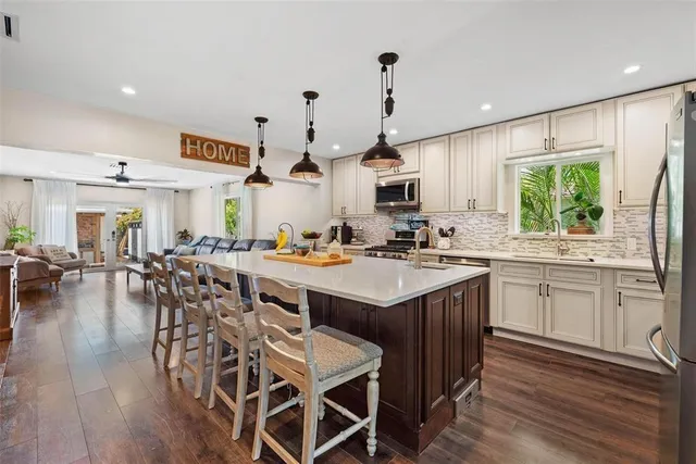 a kitchen with stainless steel appliances a table chairs sink and cabinets