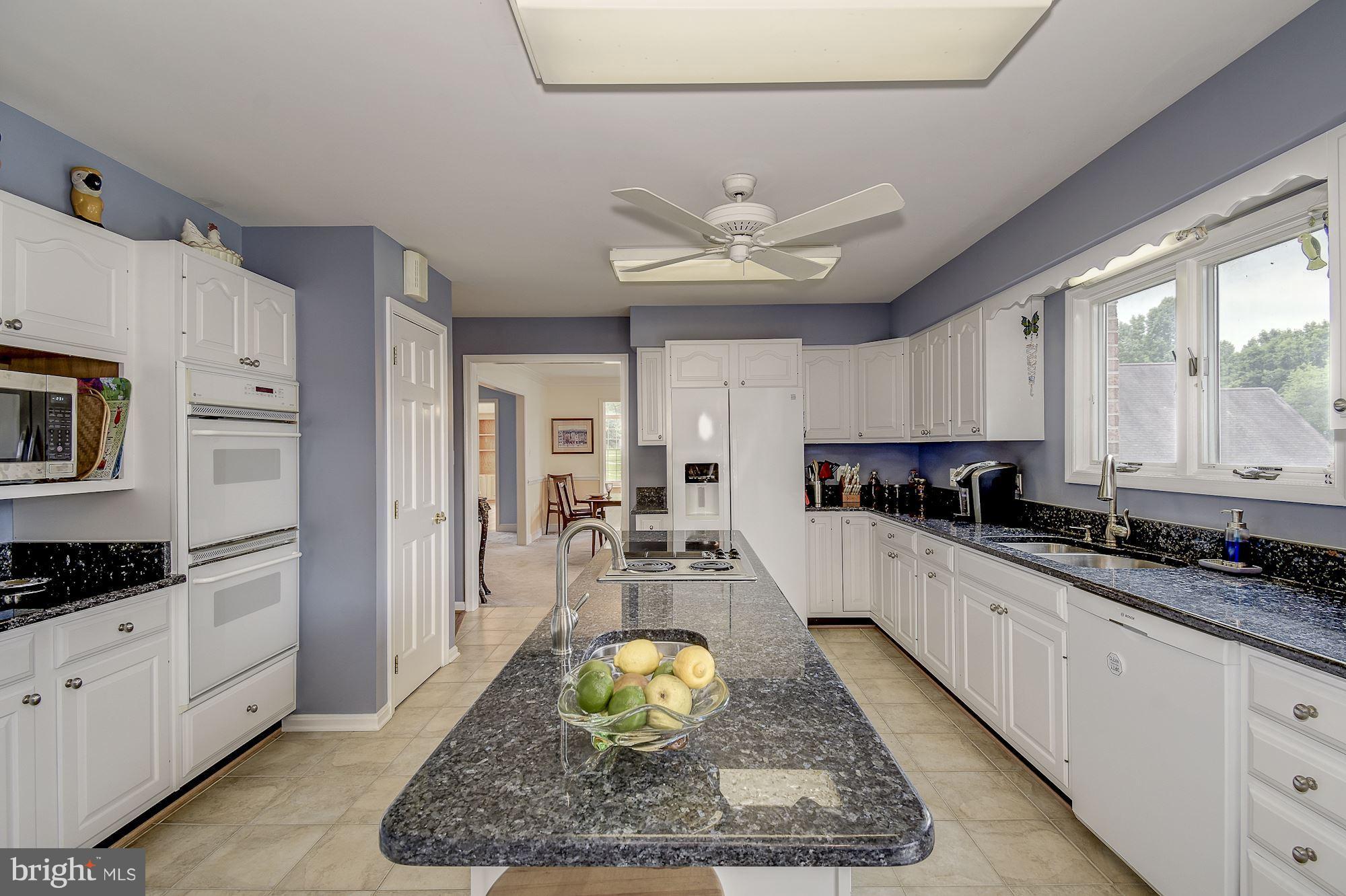 10920 Ward Road Dunkirk, MD 20754 - Photo 15 of 63 a large kitchen with kitchen island granite countertop a stove a sink a refrigerator and white cabinets with wooden floor