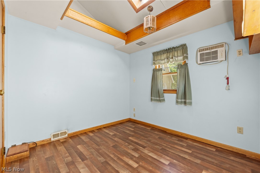 409 Edith Avenue Akron, OH 44312 - Photo 22 of 45 Room featuring wood-finish flooring, a window with wood trim, an exposed wood beam ceiling, and a ceiling-mounted light fixture