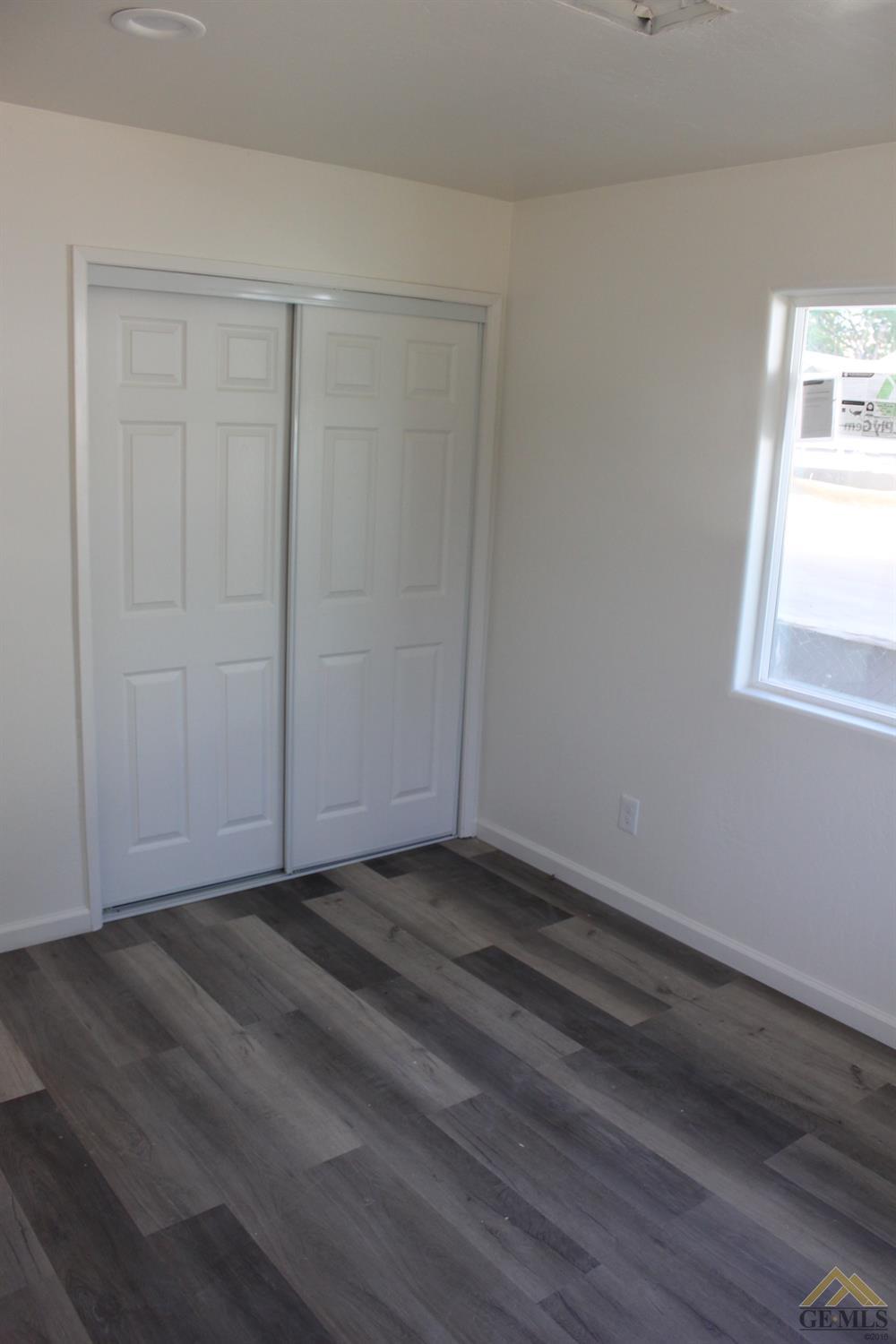 Undisclosed Address Wasco, CA 93280 - Photo 16 of 26 a view of an empty room with wooden floor and a window