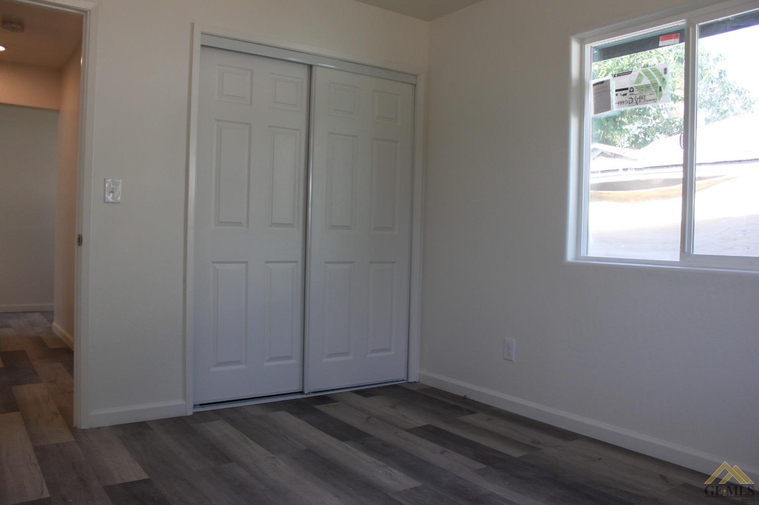 Undisclosed Address Wasco, CA 93280 - Photo 18 of 26 an empty room with wooden floor and windows